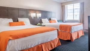 北湾Knights Inn North Bay的酒店客房带两张带橙色床单的床