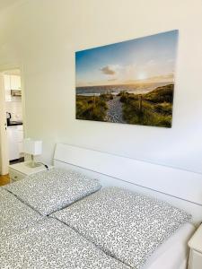 诺德施泰特Bungalow-Wohnung nahe Flughafen Hamburg的白色卧室配有一张床,墙上挂着一幅画