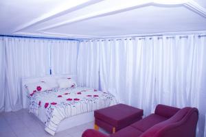 科托努Hôtel Amazone的白色卧室配有床和沙发