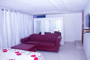 科托努Hôtel Amazone的客厅配有红色的沙发和床。