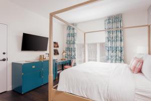 彭萨科拉Lily Hall的一间卧室配有一张带蓝色梳妆台的床和电视。