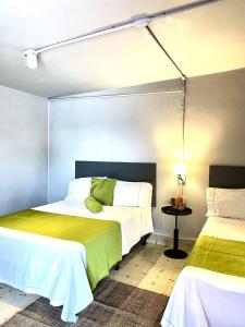 马特瓦拉Hotel El Pedregal的一间卧室配有两张带白色和绿色床单的床