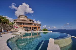Tortola IslandThe Aerial, BVI All-Inclusive Private Island的一座游泳池位于一座毗邻大海的建筑前