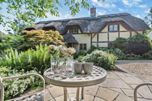 BreamoreThe Cottage, Beautiful New Forest 5 Bedroom Thatched Cottage的一张桌子,上面有花瓶和两个杯子