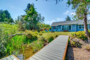 洋滨市Canal Cottage Retreat with Dock and Waterfront Views的庭院前的蓝色房子,有木路