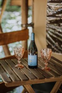 希欧福克Sioglamping in Siocamping的木桌旁的一瓶葡萄酒和两杯酒