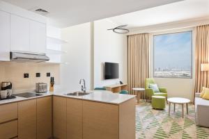 迪拜Holiday Inn & Suites - Dubai Science Park, an IHG Hotel的厨房和带大窗户的客厅