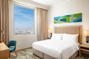 迪拜Holiday Inn & Suites - Dubai Science Park, an IHG Hotel的酒店客房设有床和窗户。