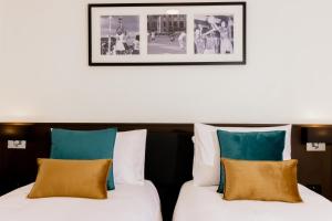 苏瓦Capricorn Hotel Suva的两张位于酒店客房的床,墙上挂着照片