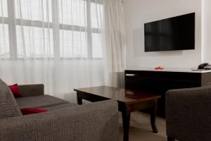 苏瓦Capricorn Hotel Suva的客厅配有电视、沙发和桌子