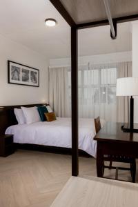 苏瓦Capricorn Hotel Suva的一间卧室配有两张床、一张桌子和一张书桌