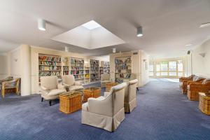 霍恩斯比Wahroonga Furnished Apartments的图书馆配有桌椅和书架