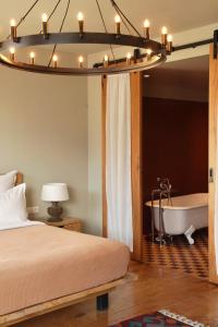 卡兹贝吉卡兹别吉客房酒店的一间卧室配有一张床、一个浴缸和一个吊灯。