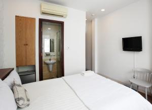 胡志明市Nguyen Thanh Hotel的一间带白色床的卧室和一间浴室