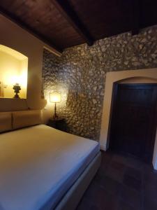RacalmutoVILLA ALESSI - dimora storica的一间卧室设有一张床和石墙