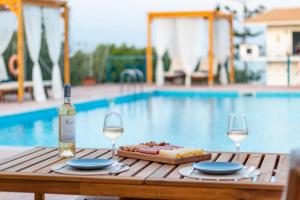 科罗尼Koroni Xenios Zeus, Seaview Summer Retreats的一张桌子,上面放着一瓶葡萄酒和两杯酒