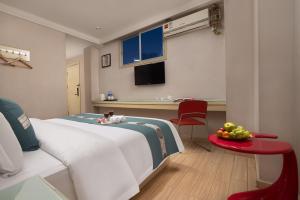 花都Kaiserdom Hotel Baiyun Airport-24-hour Airport-Free shuttle bus的一间卧室配有一张床和一张桌子及一碗水果