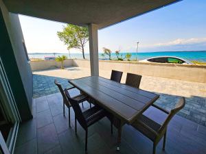 宁Apartmani Adria的一个带木桌和椅子的海滩庭院