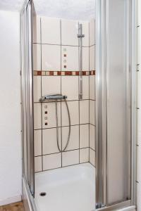 Ferienwohnung am Sachsenring的浴室铺有白色瓷砖,设有淋浴。