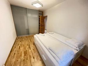 克拉科夫Apartament Park Zakrzowek的卧室配有白色的床,铺有木地板