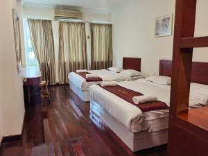 马六甲SC Hotel Melaka的客房内设有两张床,铺有木地板,设有窗户。