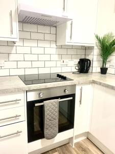哈罗Flat in London- Modern 2 Bedroom Apartment Harrow near Wembley的白色的厨房配有炉灶和微波炉。