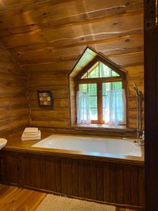 RokytneLisotel的木制客房设有一个大型浴缸,配有窗户