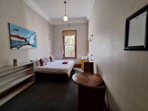 开普敦Ashanti Lodge Backpackers的一间卧室配有一张床、一张桌子和一个窗户。