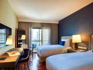 里约热内卢Fairmont Rio de Janeiro Copacabana的酒店客房配有两张床和一张书桌