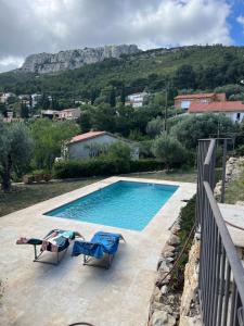 土伦Hauteurs de Toulon : Charmant studio piscine的一个带两把椅子的游泳池和一个山