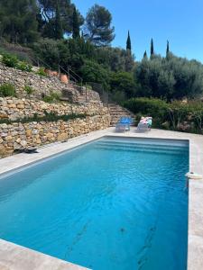 土伦Hauteurs de Toulon : Charmant studio piscine的一个带两把椅子和石墙的游泳池