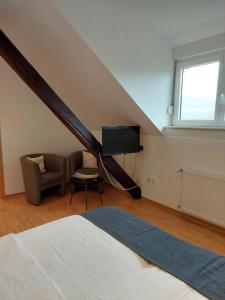 布劳讷贝格Weingut Licht-Stadtfeld的一间卧室配有一张床、一台电视和一把椅子