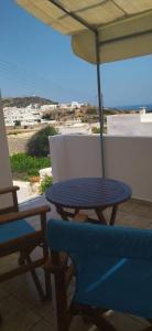 基莫洛斯岛Elzahed apartments bonaccia的阳台配有蓝色的桌椅和遮阳伞