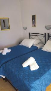 基莫洛斯岛Elzahed apartments bonaccia的卧室内的两张床,配有蓝色床单和白色毛巾