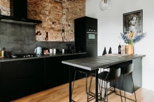 米德尔堡Number 9 holiday apartments的厨房配有黑色橱柜和带凳子的台面