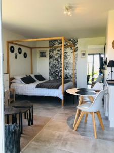 翁弗勒尔Bel Air Studios-Terrasse couverte-Jardinet-Vue Pont de Normandie-Parking privé的卧室配有一张床和一张桌子及椅子