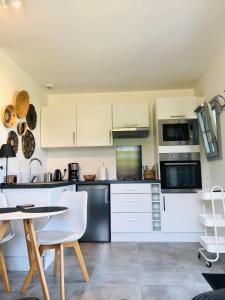 翁弗勒尔Bel Air Studios-Terrasse couverte-Jardinet-Vue Pont de Normandie-Parking privé的厨房配有白色橱柜和桌椅