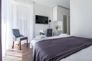 库瑞尼卡慕斯卡Port 21 Pura Pool & Design Hotel - Adults Only的一间卧室配有一张床、一把椅子和电视。