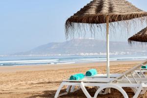 阿加迪尔Iberostar Founty Beach All Inclusive的海滩上的沙滩椅和遮阳伞