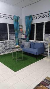居林Ketupat Palas Homestay的客厅配有蓝色的沙发和桌子