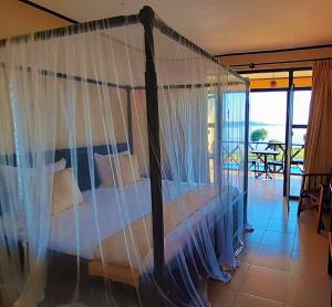 坎帕拉Kaazi Beach Resort的一间卧室设有一张天蓬床和一个阳台