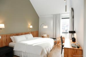 厄尔查尔坦Kaulem Hotel Boutique的卧室配有白色的床、书桌和窗户。