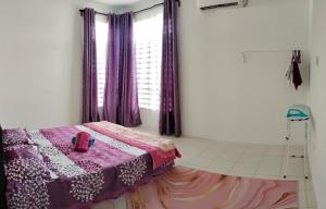 关丹FS Homestay Cherating的一间卧室配有一张带紫色窗帘的床和窗户。