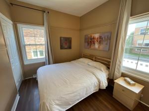 罗贝瓦勒Auberge Lac-Saint-Jean的卧室配有白色的床和2扇窗户。