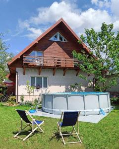 米奇科夫采Agroturystyka U Głuszków的一座带两把椅子的房子和一座庭院内的游泳池