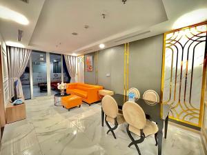 胡志明市Vinhome Central Park Apartment的客厅配有橙色的沙发、桌子和椅子