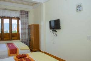 峰牙HOA PHUONG PHONG NHA Hotel的一间卧室设有两张床,墙上配有电视。