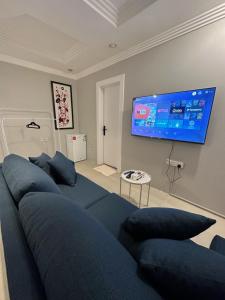 利雅德Villa Apartments的客厅配有蓝色的沙发和平面电视。
