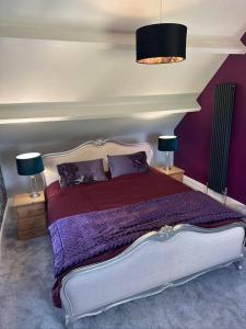 彭里斯The Coach House 1861的一间卧室配有一张带紫色床单的床和两盏灯。