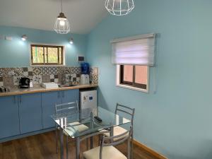 安加罗阿Cabañas Raupa的蓝色的厨房,配有玻璃桌和椅子